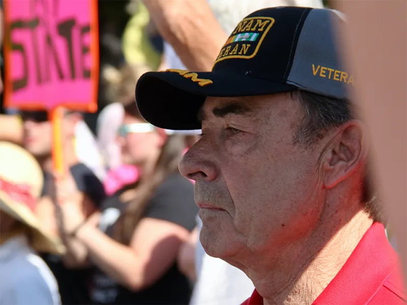 male veteran in hat looks on during rally